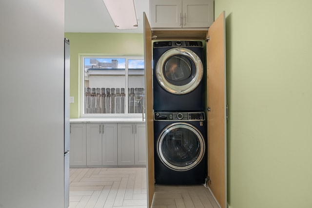 laundry area featuring stacked washer and dryer and light parquet floors