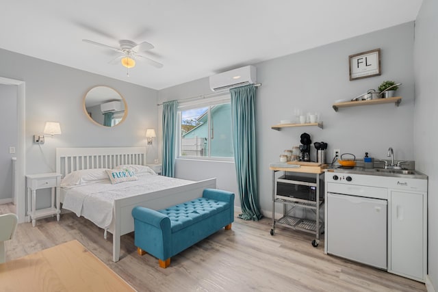 bedroom with an AC wall unit, ceiling fan, sink, and light wood-type flooring