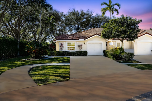 mediterranean / spanish house featuring a yard and a garage