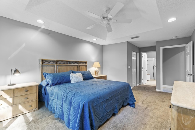 bedroom with a textured ceiling, a raised ceiling, ceiling fan, a closet, and carpet floors