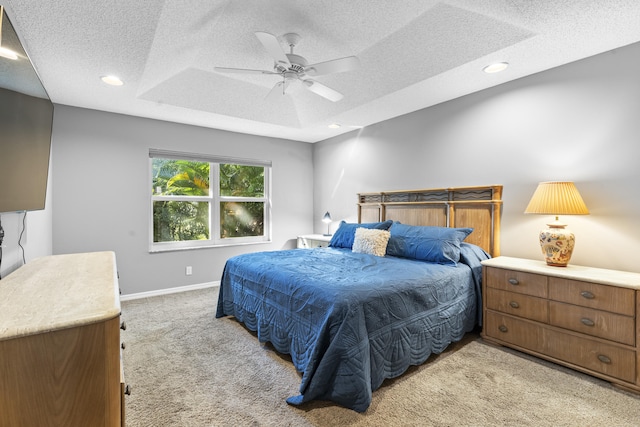 carpeted bedroom with ceiling fan, a raised ceiling, and a textured ceiling