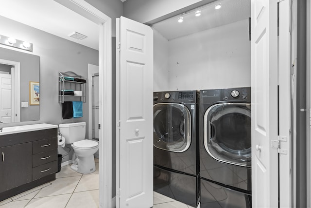 laundry area with sink, washing machine and dryer, a textured ceiling, and light tile patterned floors