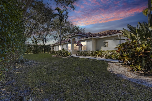 property exterior at dusk featuring a lawn