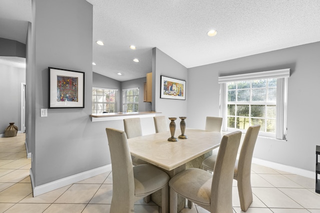 dining space featuring a textured ceiling, light tile patterned flooring, and vaulted ceiling