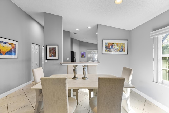 dining area featuring a textured ceiling, lofted ceiling, and light tile patterned floors