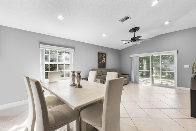 dining room with lofted ceiling, a textured ceiling, ceiling fan, and light tile patterned floors