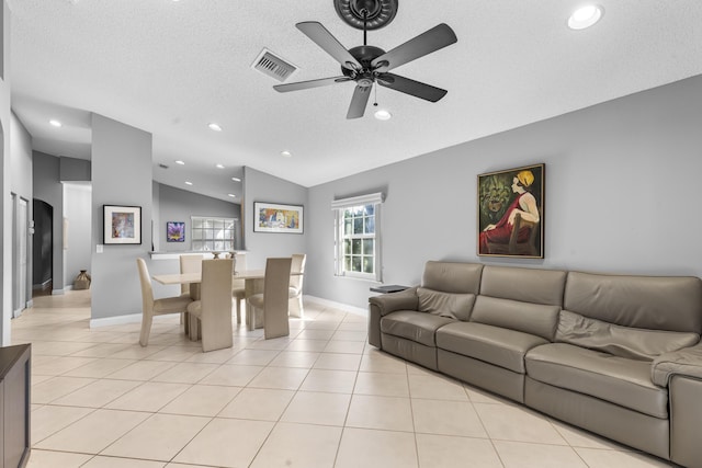 living room featuring ceiling fan, vaulted ceiling, light tile patterned flooring, and a textured ceiling