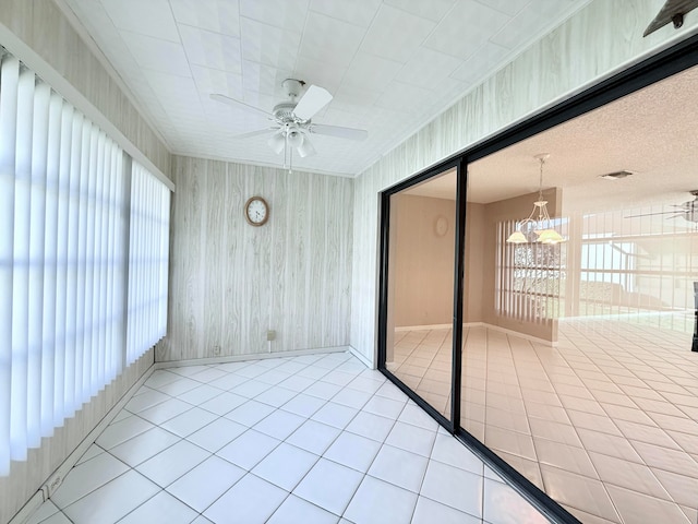 unfurnished sunroom with ceiling fan with notable chandelier