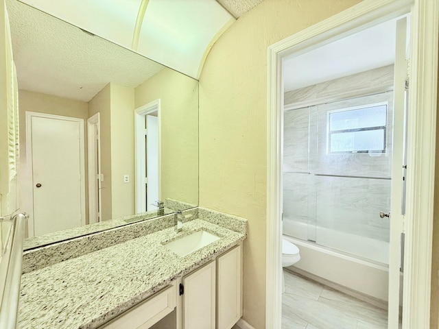 full bathroom with vanity, enclosed tub / shower combo, a textured ceiling, and toilet