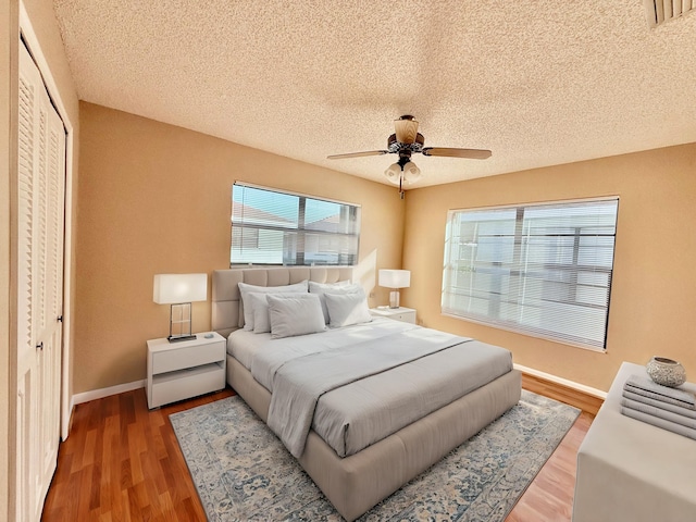 bedroom featuring hardwood / wood-style floors, ceiling fan, a textured ceiling, and a closet