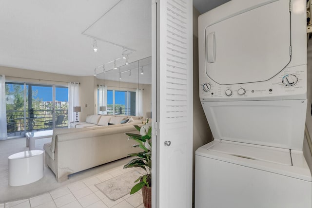 clothes washing area featuring stacked washer and clothes dryer and light tile patterned flooring