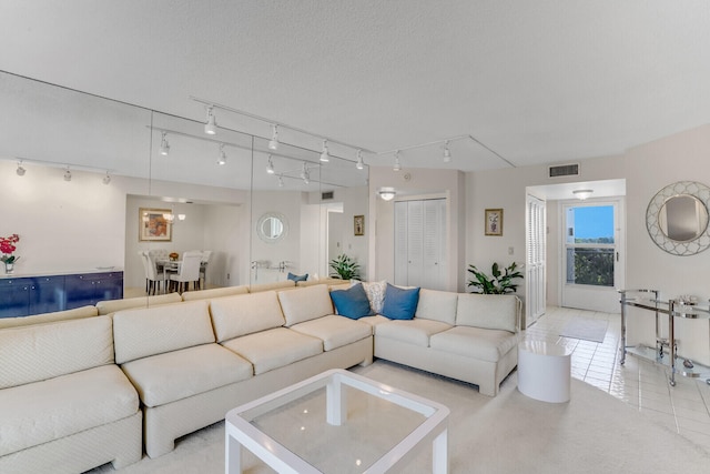 living room with light tile patterned floors, a textured ceiling, and rail lighting