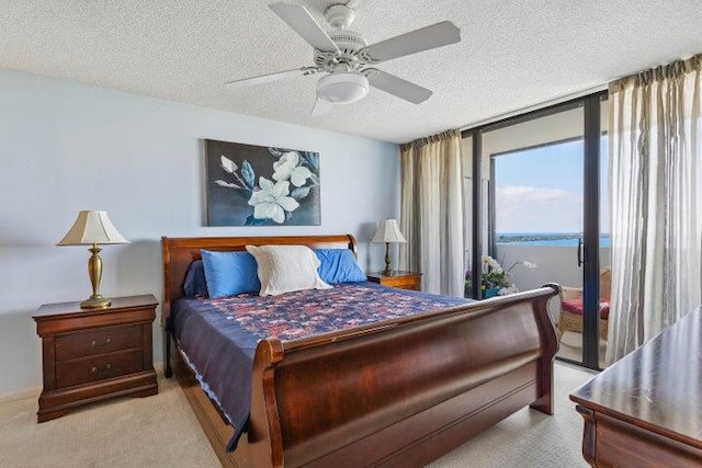 bedroom featuring ceiling fan, light colored carpet, and a textured ceiling