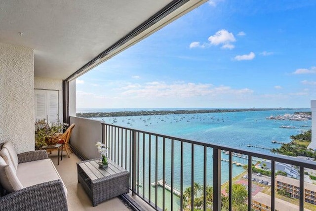 balcony with an outdoor living space and a water view