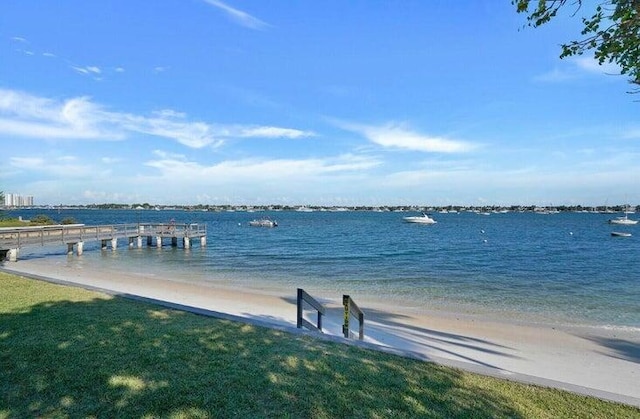 dock area featuring a water view, a beach view, and a yard