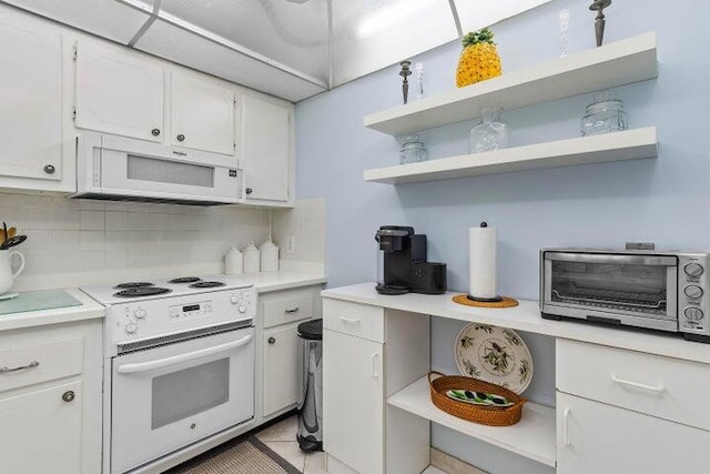 kitchen with tasteful backsplash, white cabinets, light tile patterned flooring, and white appliances