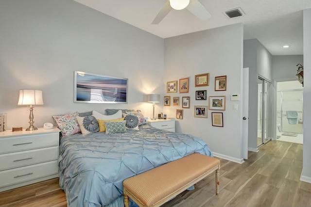 bedroom featuring ensuite bath, light hardwood / wood-style flooring, ceiling fan, and lofted ceiling