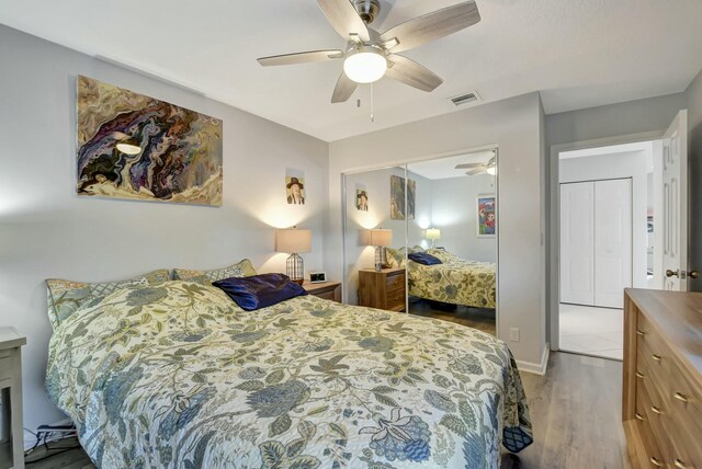 bedroom with ceiling fan, wood-type flooring, and a closet