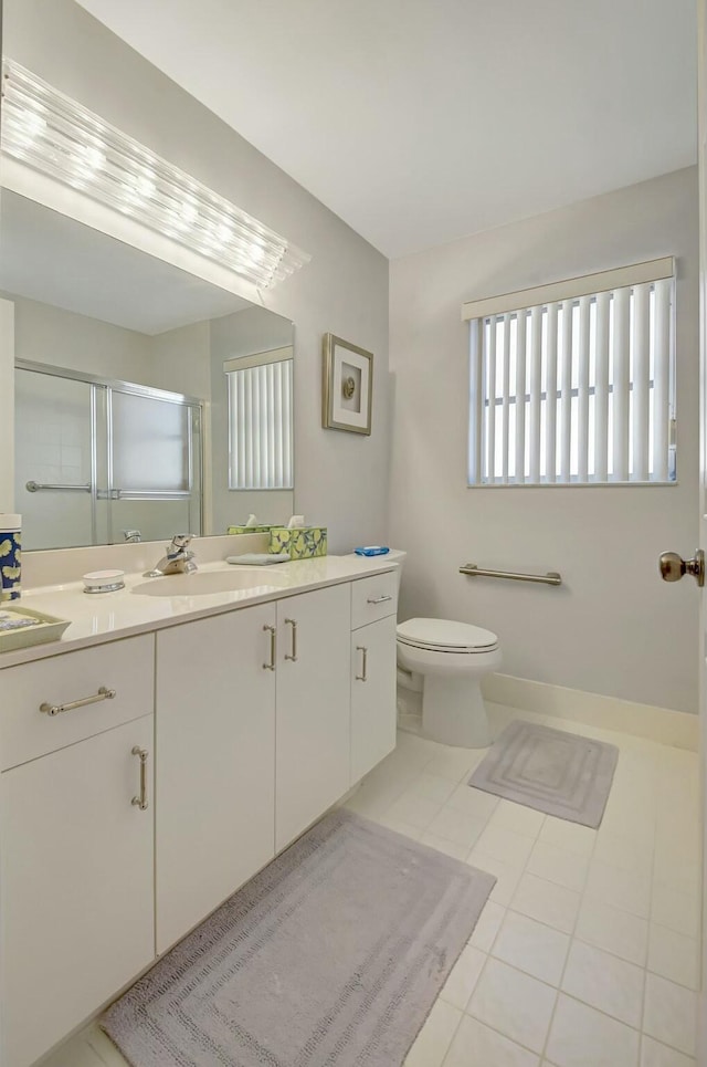 bathroom featuring tile patterned floors, vanity, toilet, and a shower with shower door