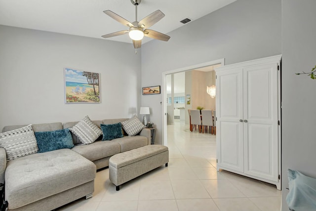 tiled living room with ceiling fan and a high ceiling