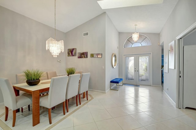 foyer entrance with french doors, light tile patterned flooring, a chandelier, and high vaulted ceiling