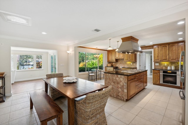 kitchen featuring plenty of natural light, a kitchen island, stainless steel appliances, and decorative light fixtures