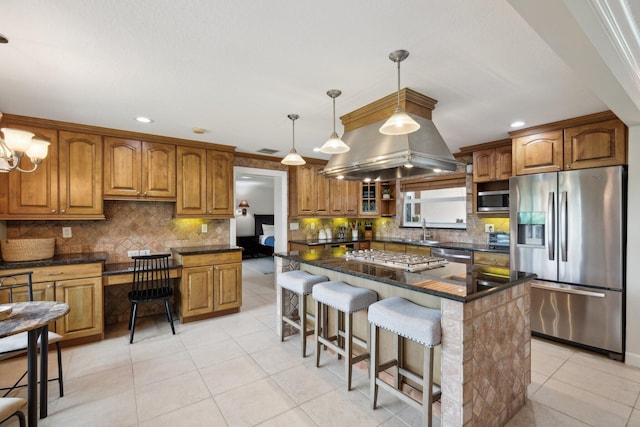 kitchen with backsplash, a kitchen breakfast bar, appliances with stainless steel finishes, decorative light fixtures, and a kitchen island