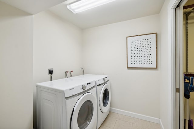 clothes washing area featuring washer and clothes dryer and light tile patterned floors