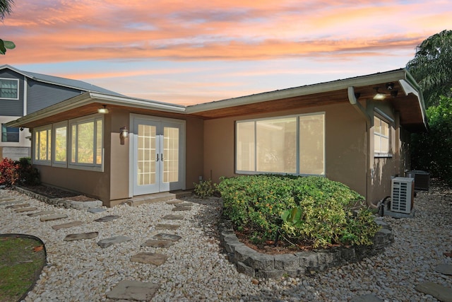 back house at dusk with french doors and cooling unit