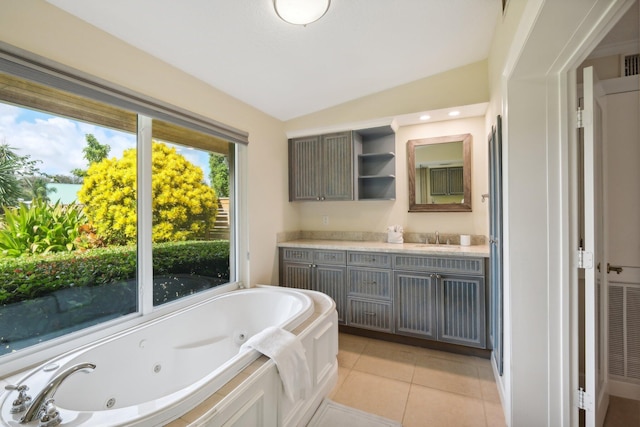 bathroom with tile patterned floors, a washtub, vanity, and vaulted ceiling