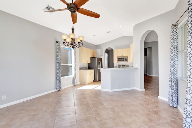 kitchen featuring vaulted ceiling, appliances with stainless steel finishes, kitchen peninsula, light tile patterned floors, and ceiling fan with notable chandelier