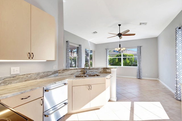 kitchen featuring sink, ceiling fan with notable chandelier, cream cabinetry, and light tile patterned floors