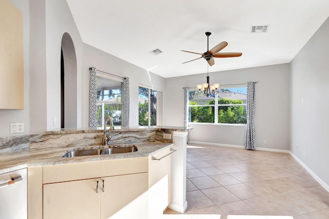 kitchen featuring light stone countertops, dishwasher, light tile patterned floors, ceiling fan with notable chandelier, and sink