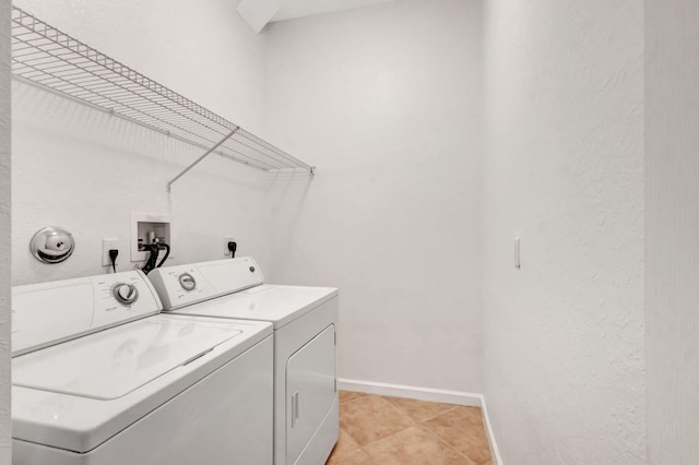 clothes washing area with washer and dryer and light tile patterned floors