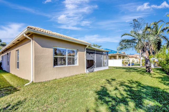 rear view of property with a lawn and a sunroom