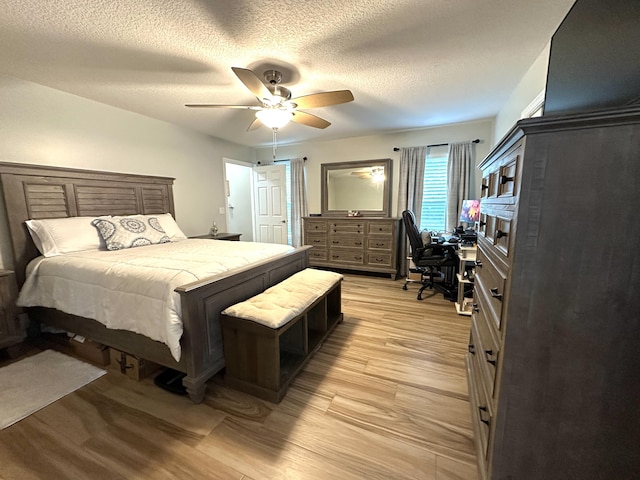 bedroom featuring ceiling fan, light wood-type flooring, and a textured ceiling