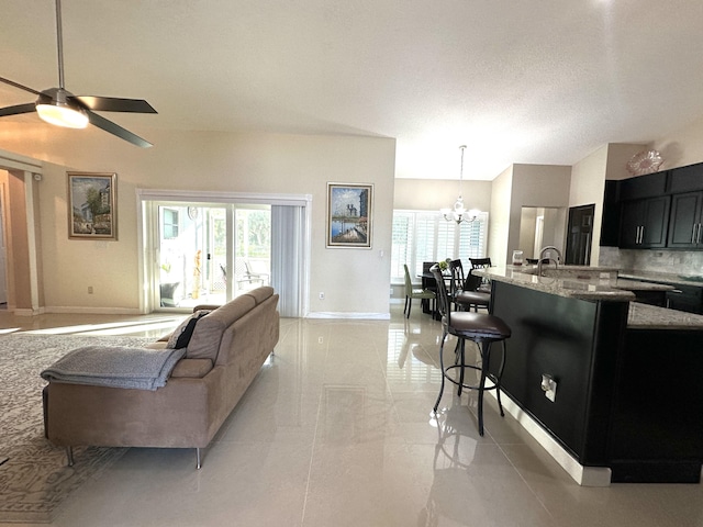 living room featuring ceiling fan with notable chandelier, a textured ceiling, and a wealth of natural light