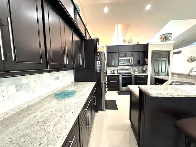 kitchen featuring backsplash, light stone counters, sink, and appliances with stainless steel finishes