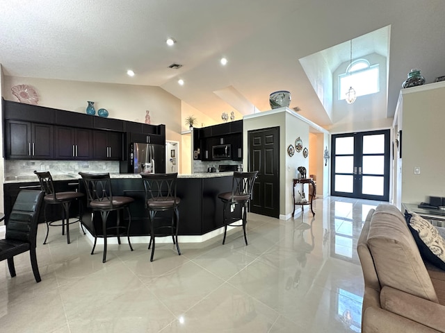 kitchen featuring a kitchen breakfast bar, decorative backsplash, plenty of natural light, and appliances with stainless steel finishes