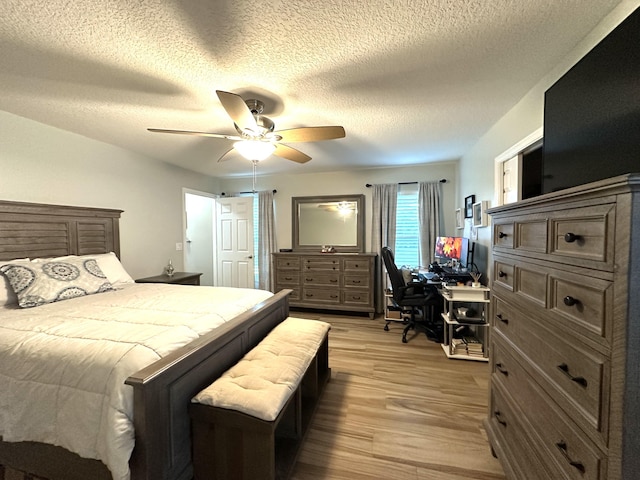 bedroom featuring ceiling fan, light wood-type flooring, and a textured ceiling