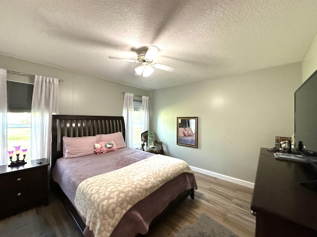 bedroom featuring multiple windows, ceiling fan, dark wood-type flooring, and a textured ceiling