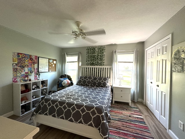 bedroom featuring hardwood / wood-style floors, ceiling fan, multiple windows, and a closet