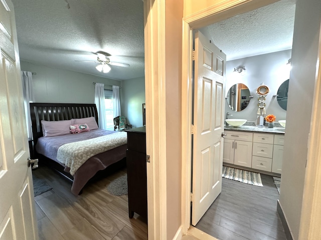 bedroom featuring wood-type flooring, a textured ceiling, ceiling fan, and sink