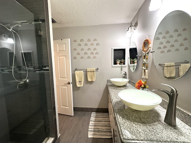 bathroom featuring hardwood / wood-style floors, vanity, a textured ceiling, and walk in shower