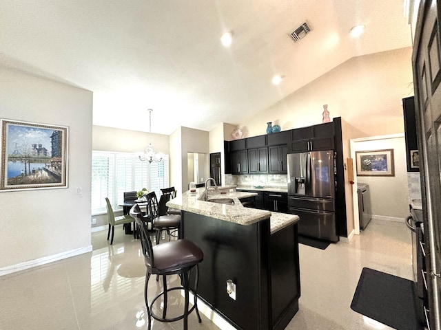 kitchen featuring stainless steel refrigerator with ice dispenser, pendant lighting, lofted ceiling, a kitchen bar, and a center island with sink