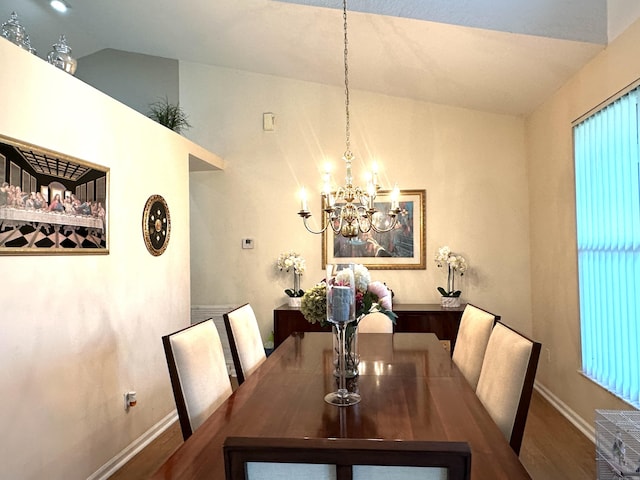 dining room with a notable chandelier, wood-type flooring, and vaulted ceiling