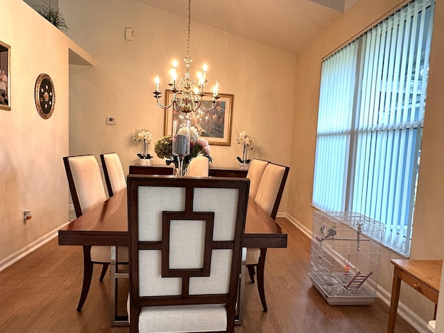 dining room with hardwood / wood-style flooring, a chandelier, and vaulted ceiling