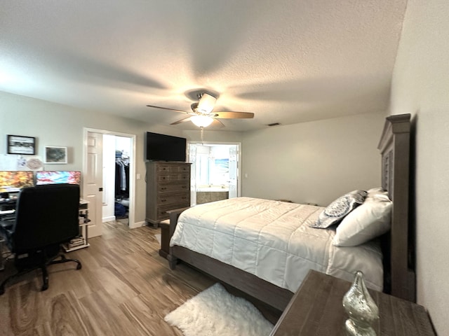 bedroom featuring ceiling fan, wood-type flooring, a textured ceiling, a walk in closet, and a closet