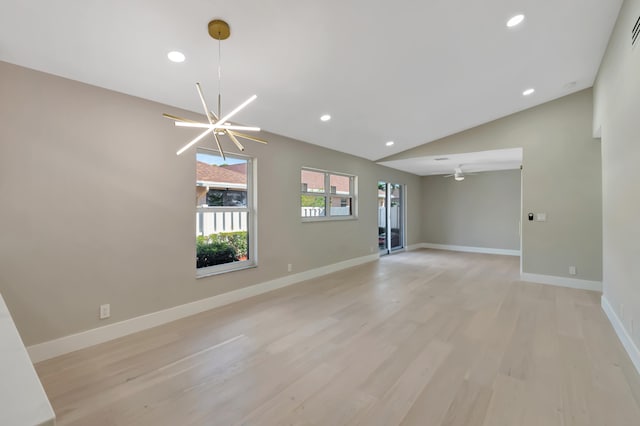 unfurnished living room with light hardwood / wood-style flooring, ceiling fan with notable chandelier, and vaulted ceiling