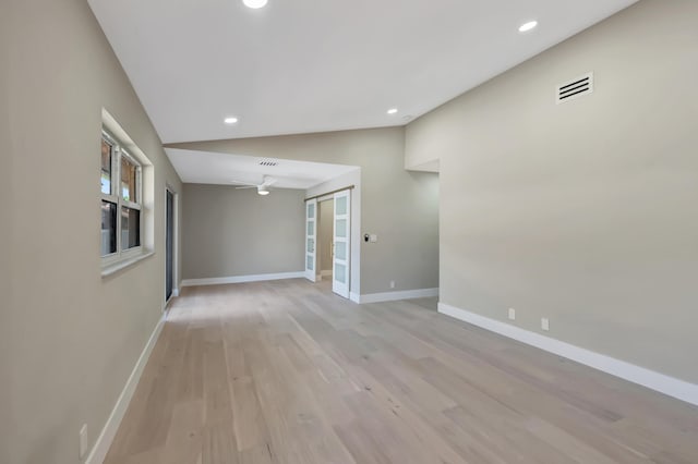 empty room featuring ceiling fan, light hardwood / wood-style floors, and vaulted ceiling